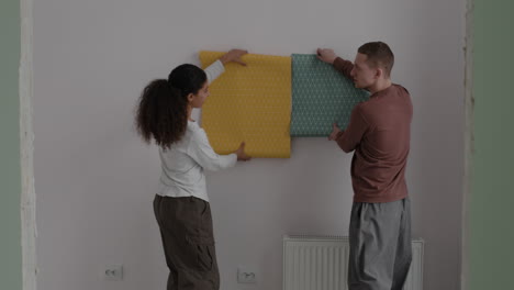 couple choosing and hanging wallpaper in their new home