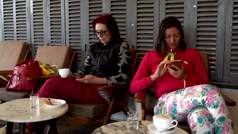 mujeres en un café están bebiendo café y usando teléfonos inteligentes
