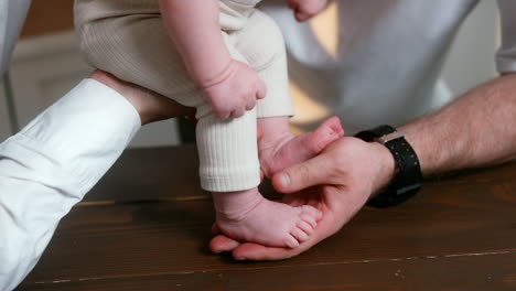 newborn baby feet stepping by the father's palm. happy newly-made parents and a family at home. close up.