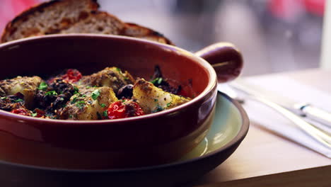 Cod-and-chorizo-bake-in-earthenware-dish-by-window,-pan