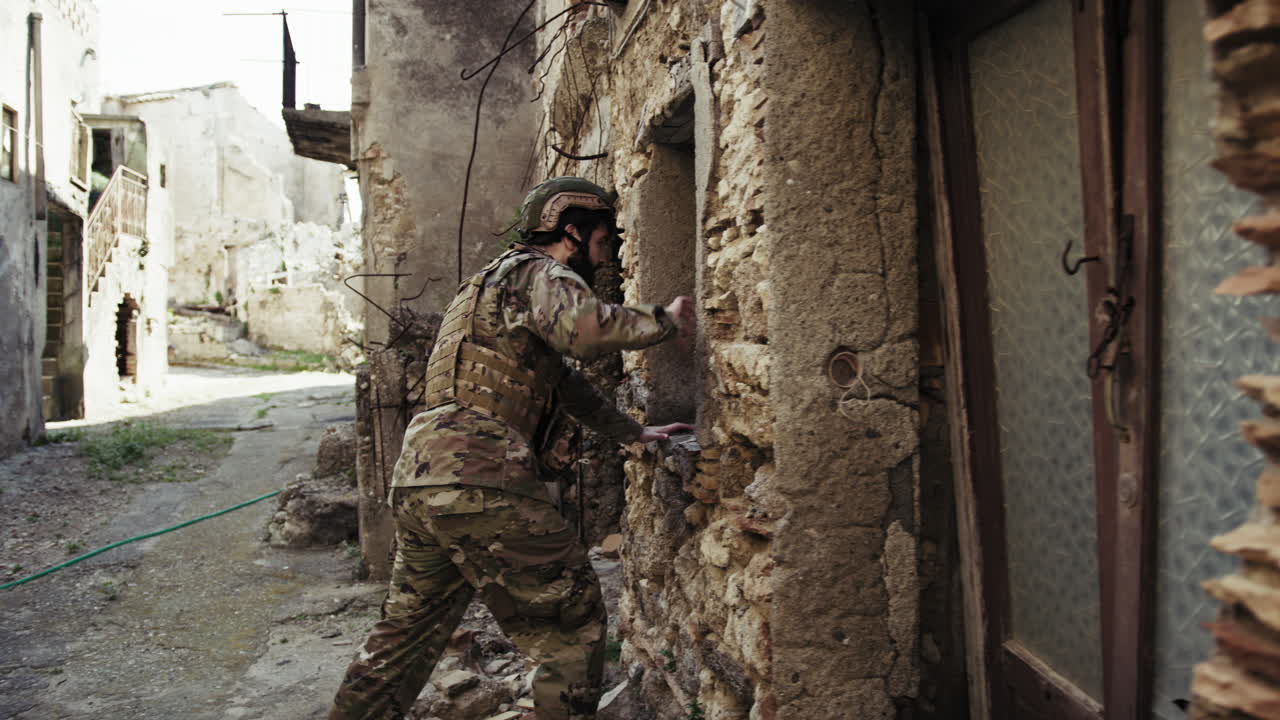 Soldier In Uniform Checks The Walls Of Destroyed Houses In The City