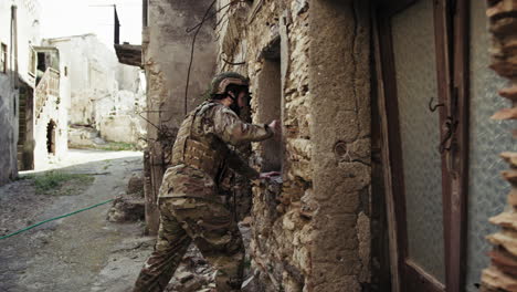 soldier in uniform checks the walls of destroyed houses in the city