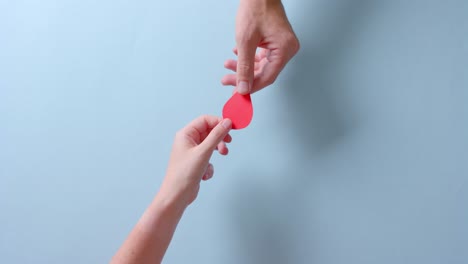 hands of caucasian people giving blood drop on blue background with copy space, slow motion