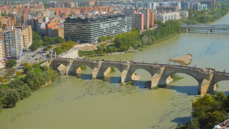 aerial view of people crossing at puente de piedra over ebro river in zaragoza, aragon, spain