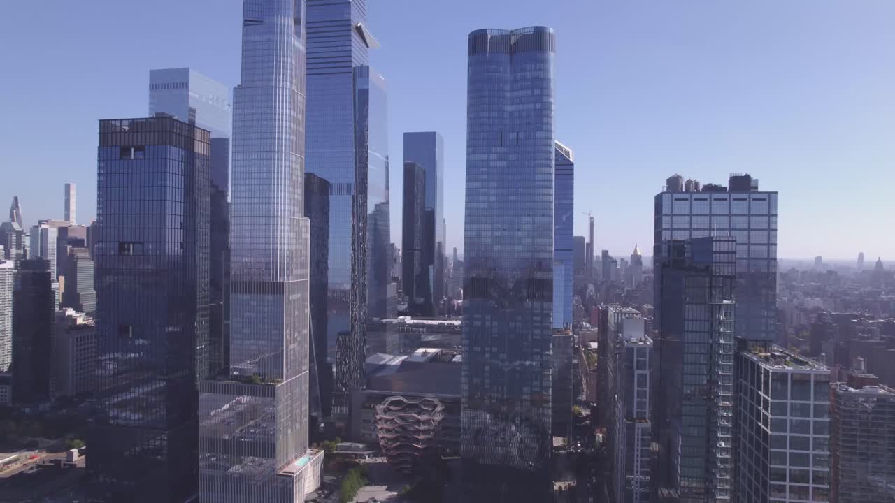 Cinematic drone pull-out revealing The Vessel and surrounding glass skyscrapers in Hudson Yards, New York City, with soft morning light and clear skies