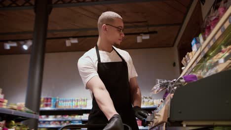 supermarket worker rearranging storage racks in veggie department, low angle view