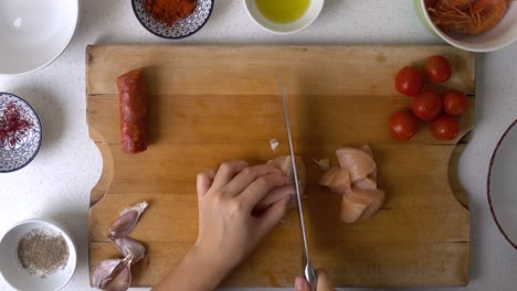 male hands using knife to cut chicken breast into bite-sized pieces