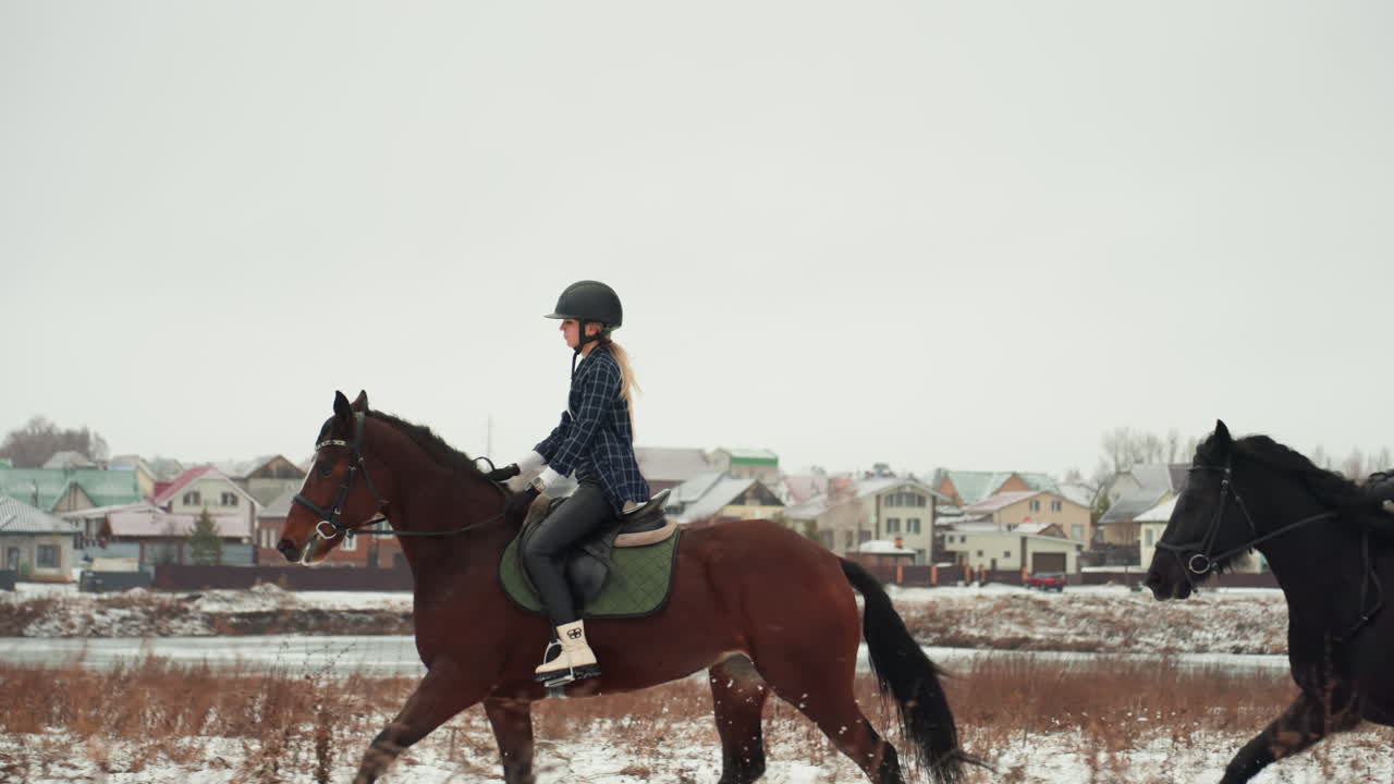 Donna caucasica che cavalca in tandem vicino al villaggio, studentessa concentrata che pratica abilità equestri durante una lezione invernale, trotto costante lungo un campo innevato, dettagli di sella e briglia del cavaliere con casco, villaggio discreto.