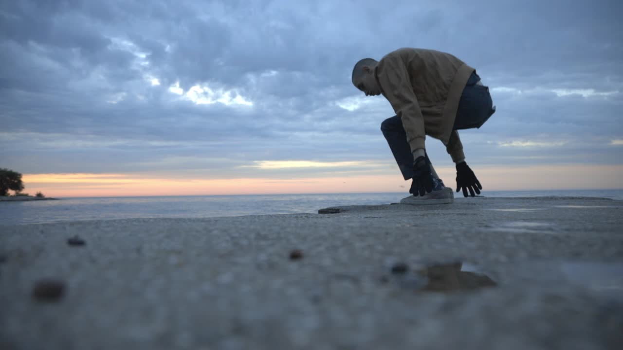 Man Walking And Sitting By The Beach Admiring The Beautiful Sunset - tilted medium shot