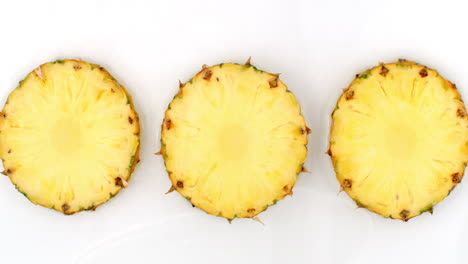 water splashes in slow motion. top view: three slices of sweet pineapple washed with water on a white background