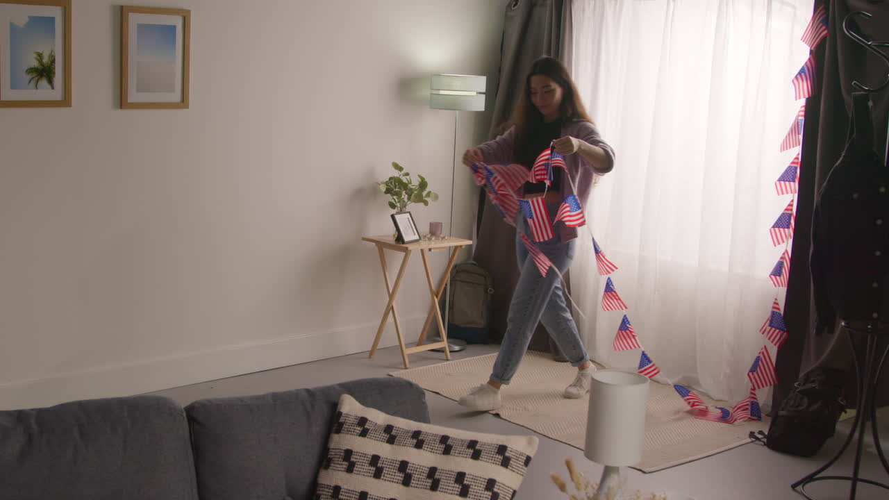 mujer en casa colgando estrellas americanas y rayas bandera bunting para la fiesta celebrando el 4 de julio día de la independencia