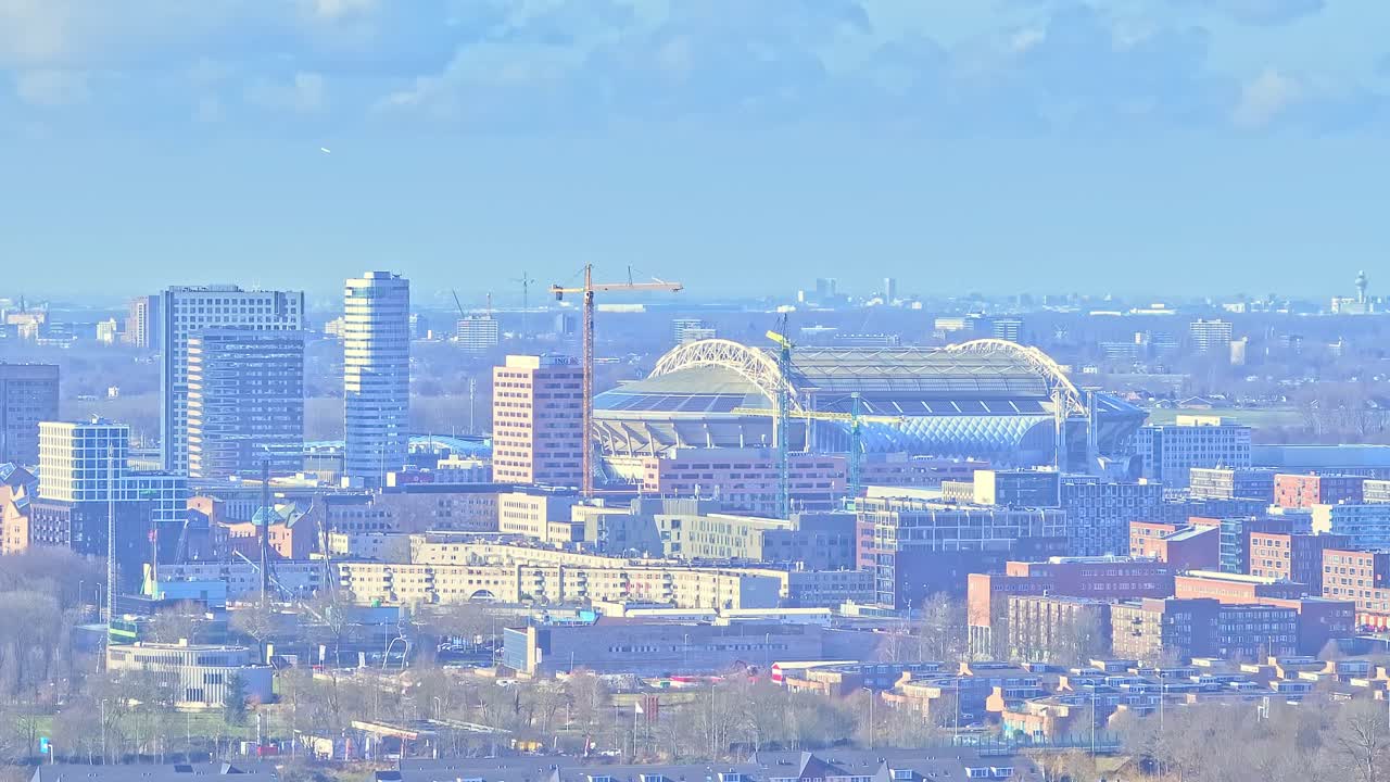 Aerial: Johan Cruyff Arena and cityscape during the day in Amsterdam, Netherlands, establishing drone shot