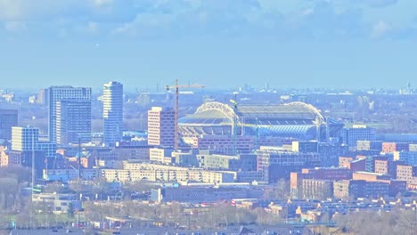 aerial: johan cruyff arena and cityscape during the day in amsterdam, netherlands, establishing drone shot