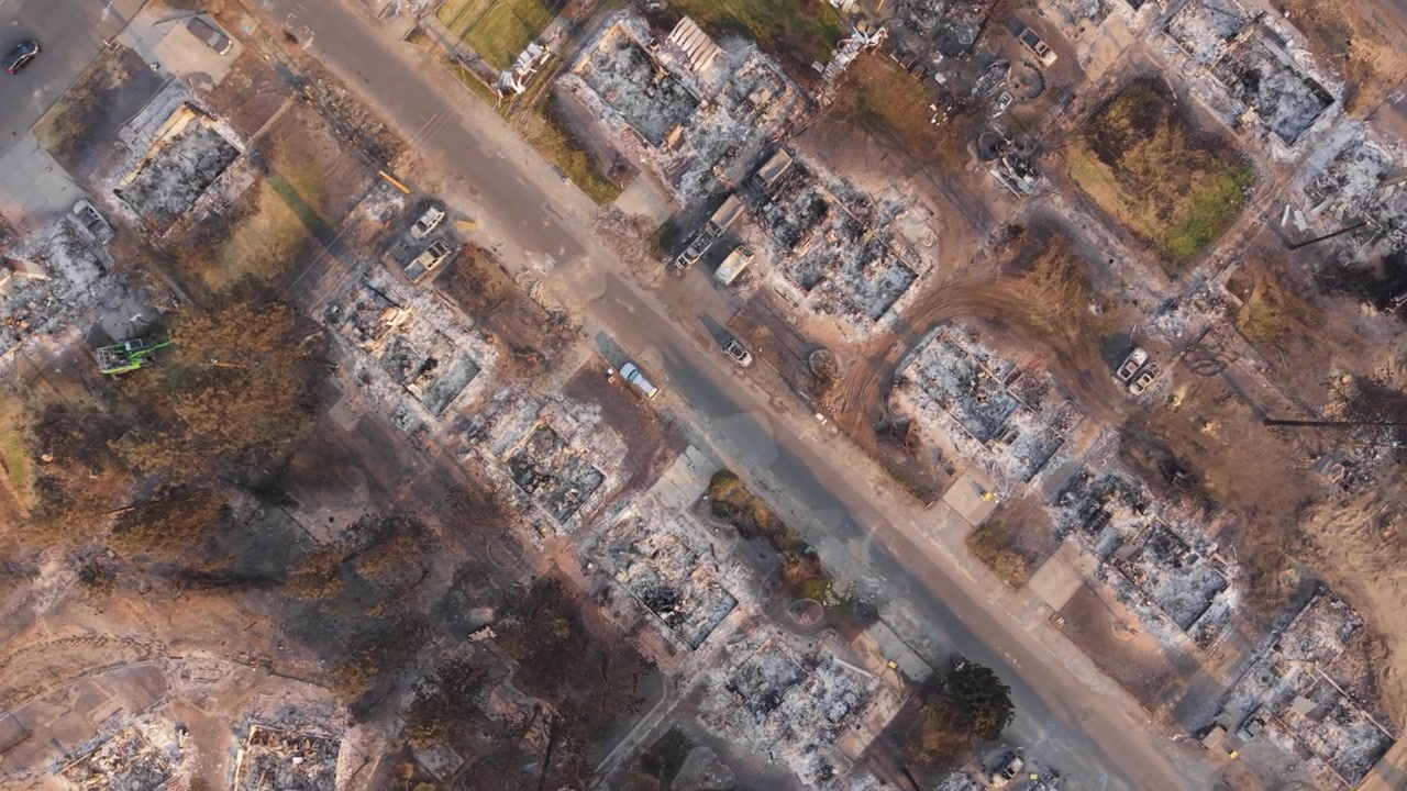 Rotating top-down aerial drone footage of wildfire destruction in Spokane, Washington, showing burned houses, charred lots and severe residential damage after the 2026 fire.