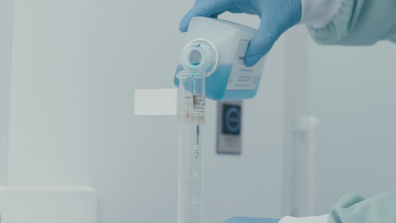 Lab worker's hand pouring serum liquid into Measuring Tube while working in Medical Drug Production