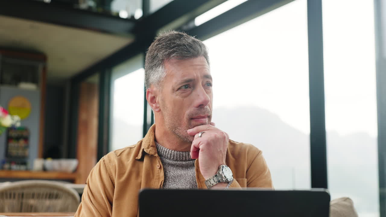 Thoughtful Man Working on Laptop at Home