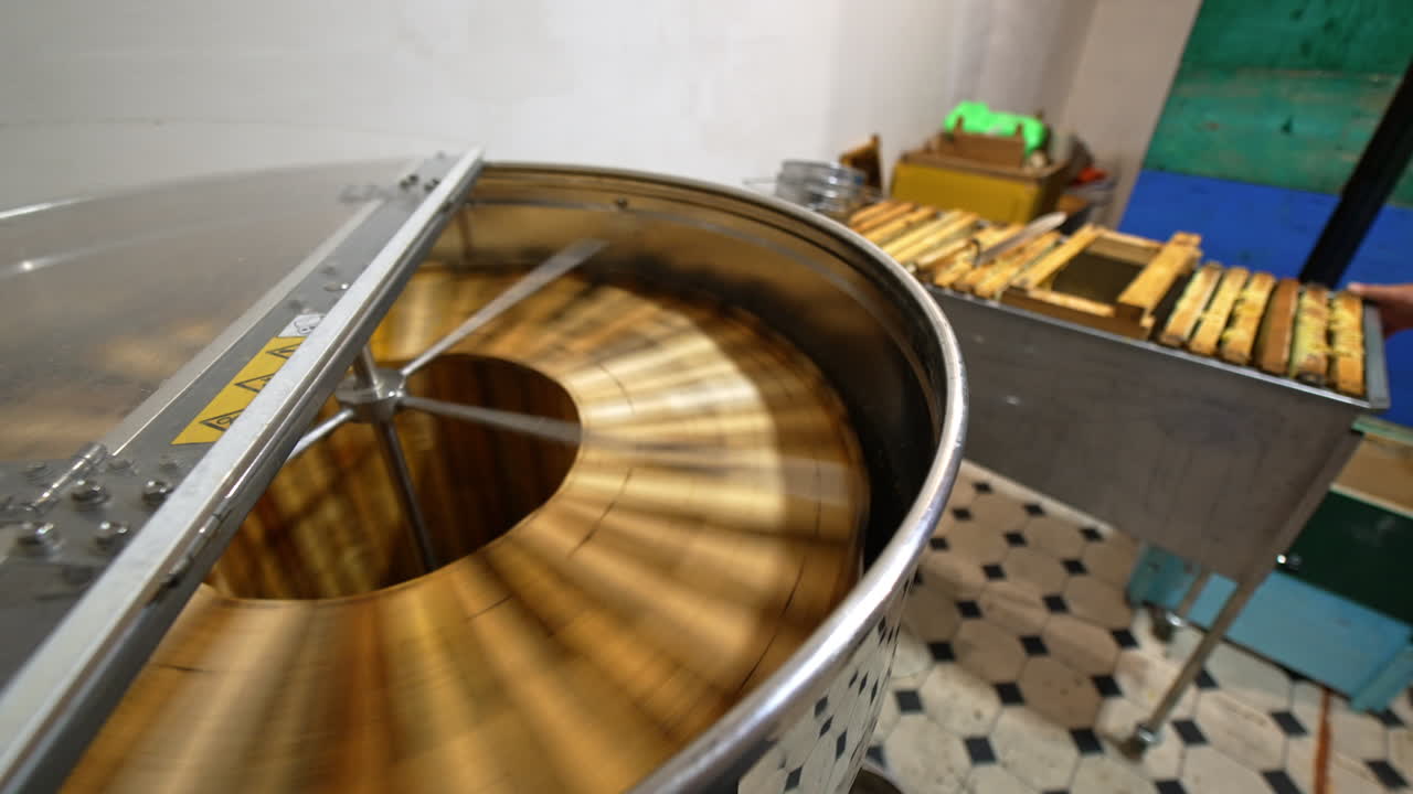 Rotating mechanism working in the centrifuge machine at apiary. Metal box full of frames standing beside. Process of organic honey extraction.