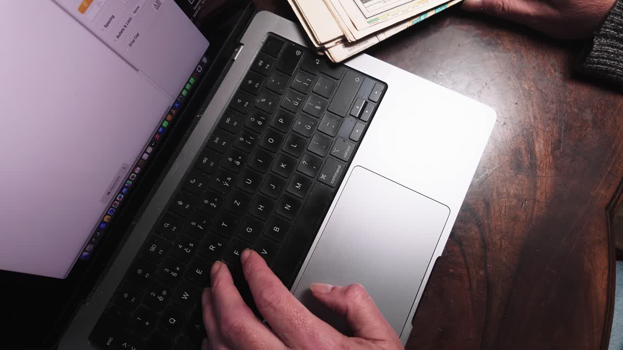 Man works from home typing on laptop keyboard in office. Top down shot