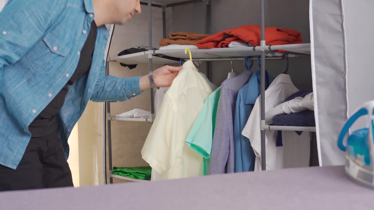 The man is choosing clothes from the closet.
