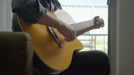 man strumming guitar at home