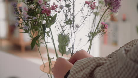 young female decorating vase with fresh flowers, floral bouquet on the table inside at home close up zoom in  4k