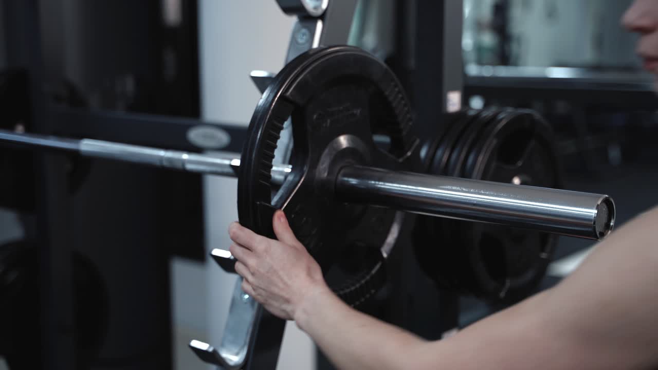 Young girl in the training in the gym. Preparation to do exercises with weights. Close-up. Professional sports equipment