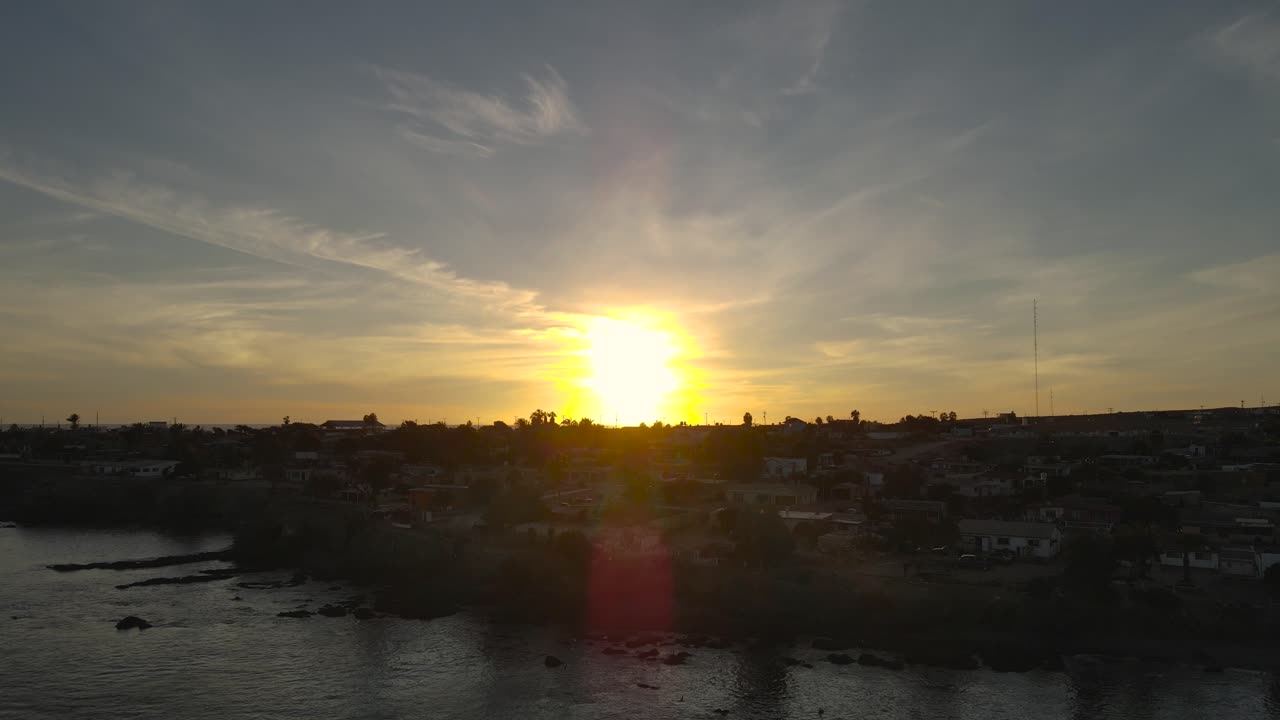 el amanecer revela la puesta de sol dorada iluminando el cielo y la ciudad costera de bahía asunción mexico