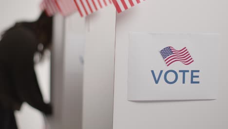 close up of voters in booths with ballot papers casting votes in american election