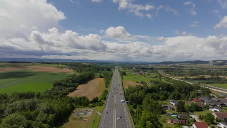 aerial view of highway with cars driving through green countryside