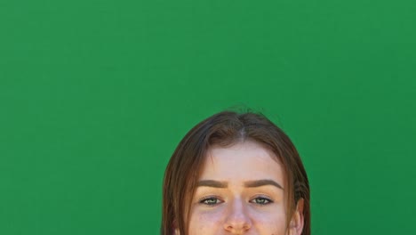 close-up of a young brunette woman which is standing in front of a green screen