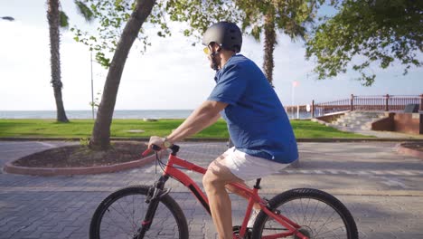 Junger-Mann,-Der-Am-Strand-Fahrrad-Fährt.