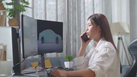 아시아 여성 자동차 디자이너가 스튜디오에서 데스크 컴퓨터에서 ev 자동차의 3d 모델을 작업하는 동안 스마트폰으로 이야기하는 측면 뷰