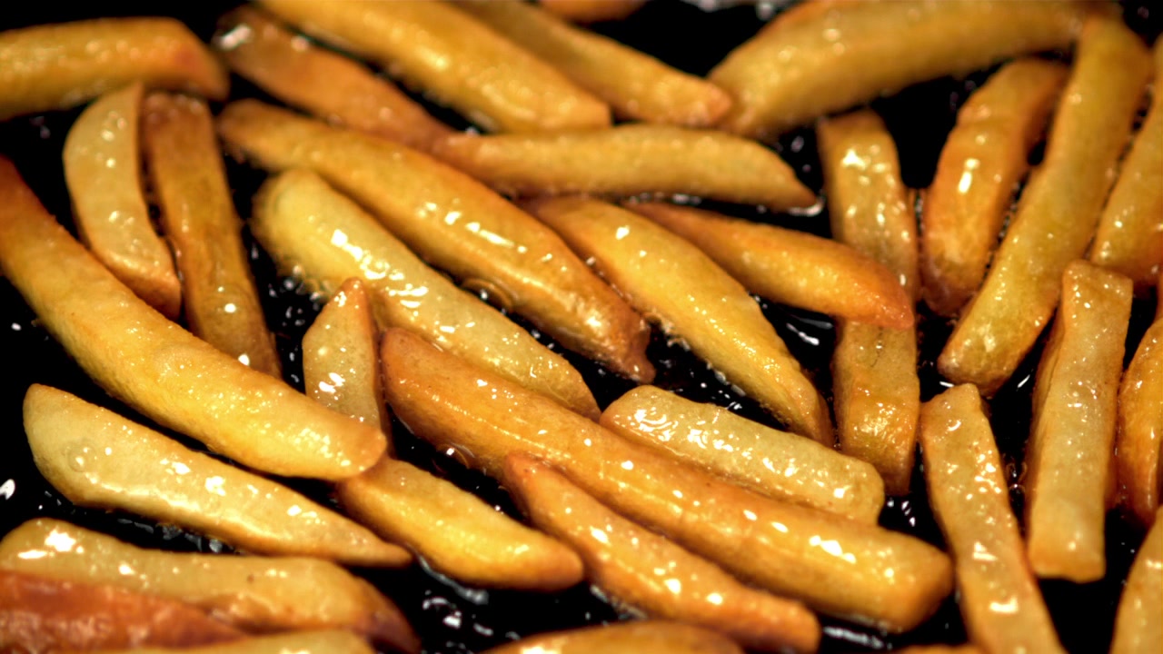 Close-up de Batatas Fritas Douradas Fritando em Óleo Quente