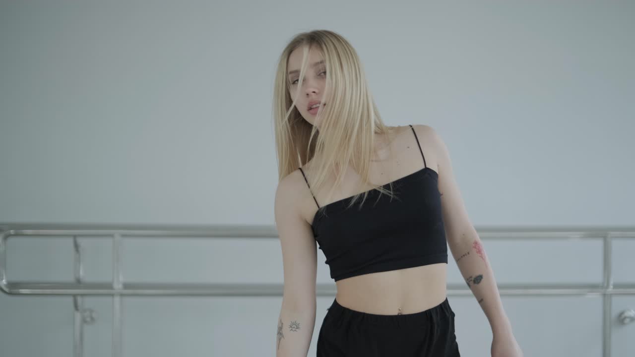 девушка в черной одежде выступает в современном стиле. танцовщица показывает плавные движения, волны тела и рук в белой комнате. современная балетная танцевальная хореография. молодая женщина движется плавно