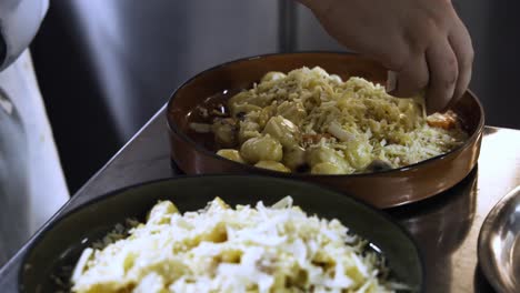 primer plano en cámara lenta del chef rociando queso rallado en el plato terminado