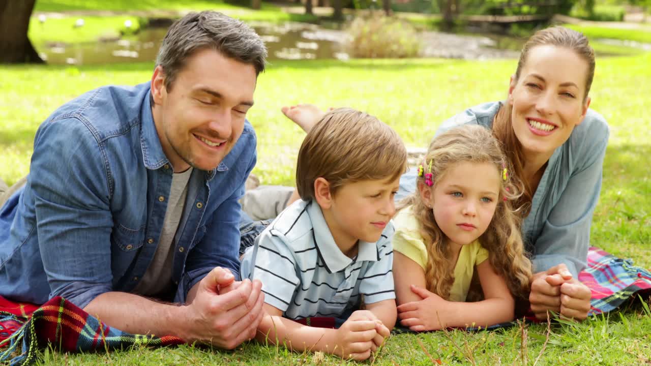 Cute family smiling at camera in the park