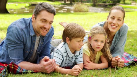 cute family smiling at camera in the park