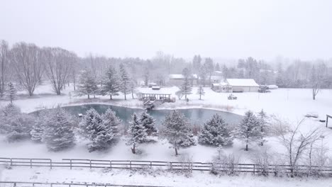 countryside home with pond in winter season on cold day, aerial side fly view