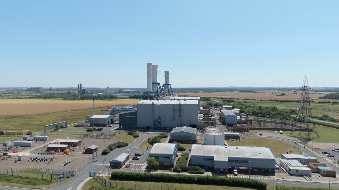 Aerial drone view of Humber South Bank power plant with smoke stacks and powerlines under sunny sky near Immingham England UK