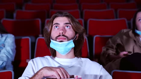 hombre viendo una película en el teatro con una máscara puesta