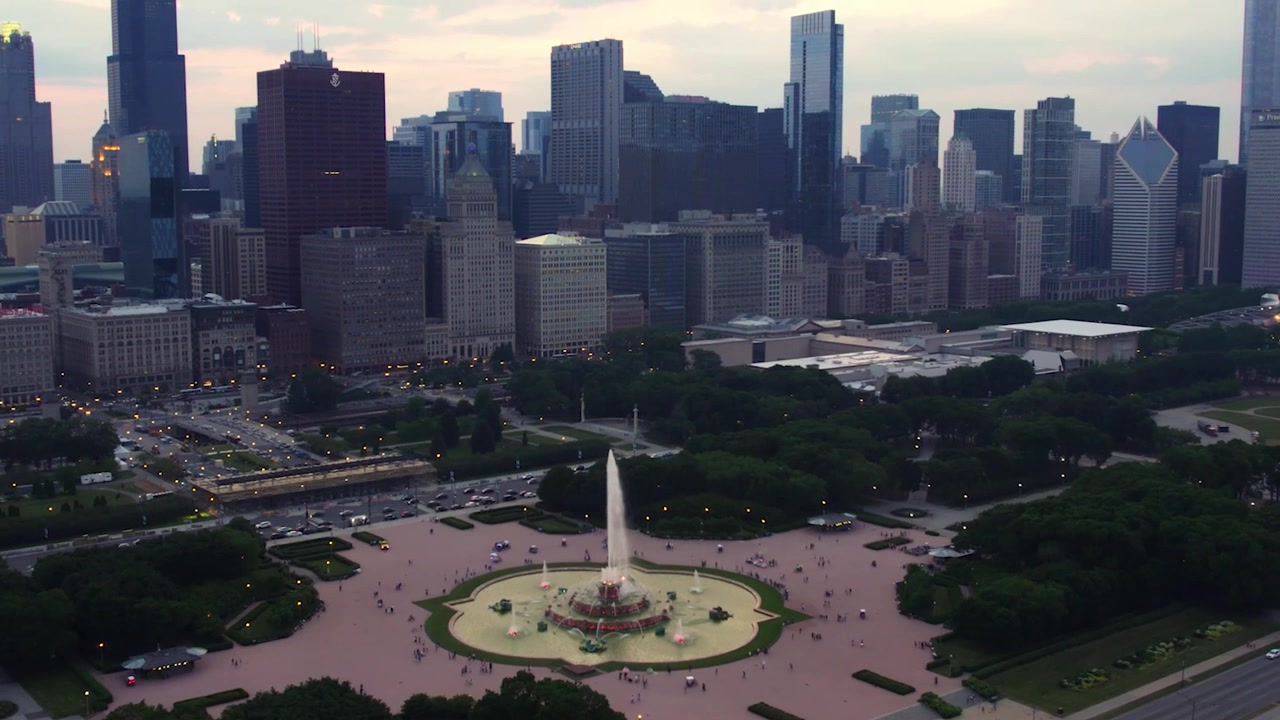 Ampia vista aerea con drone della Fontana di Buckingham a Grant Park, con i grattacieli del centro di Chicago, le strade cittadine e la morbida luce serale sullo skyline
