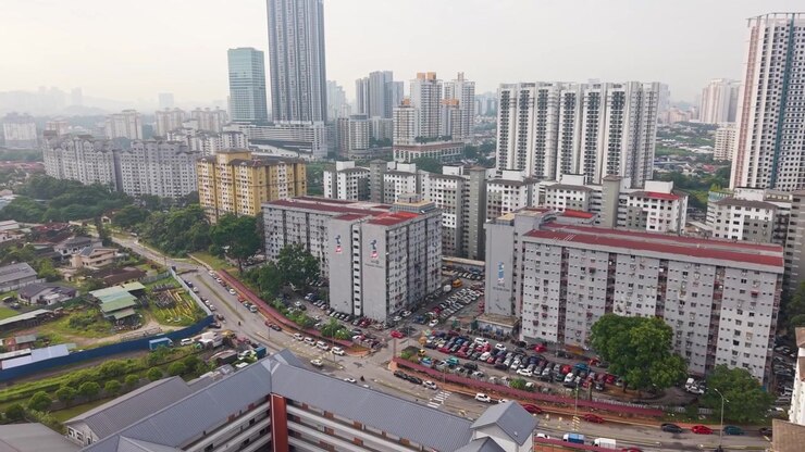 Tomada de drone com aproximação de Petaling Jaya, Malásia, mostrando um horizonte nebuloso, bairros residenciais e arranha-céus, ideal para conteúdo de desenvolvimento urbano e viagens, UHD