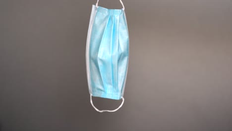 medical face mask hangs for a moment then drops to the ground - concept: covid, protection, global pandemic, safety