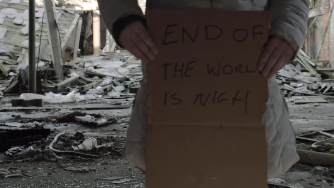 Person walking with sign warning of the end of world in collapsed building