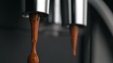 droplets of coffee dripping from espresso machine’s double portafilter spout in macro and slow motion