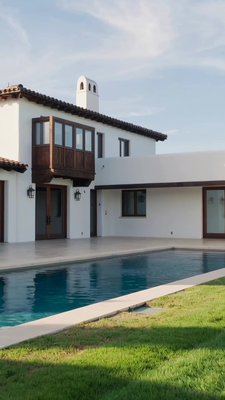 Video verticale: Telecamera che panoramica rivelando una casa mediterranea nel cortile, mostrando piscina e balcone