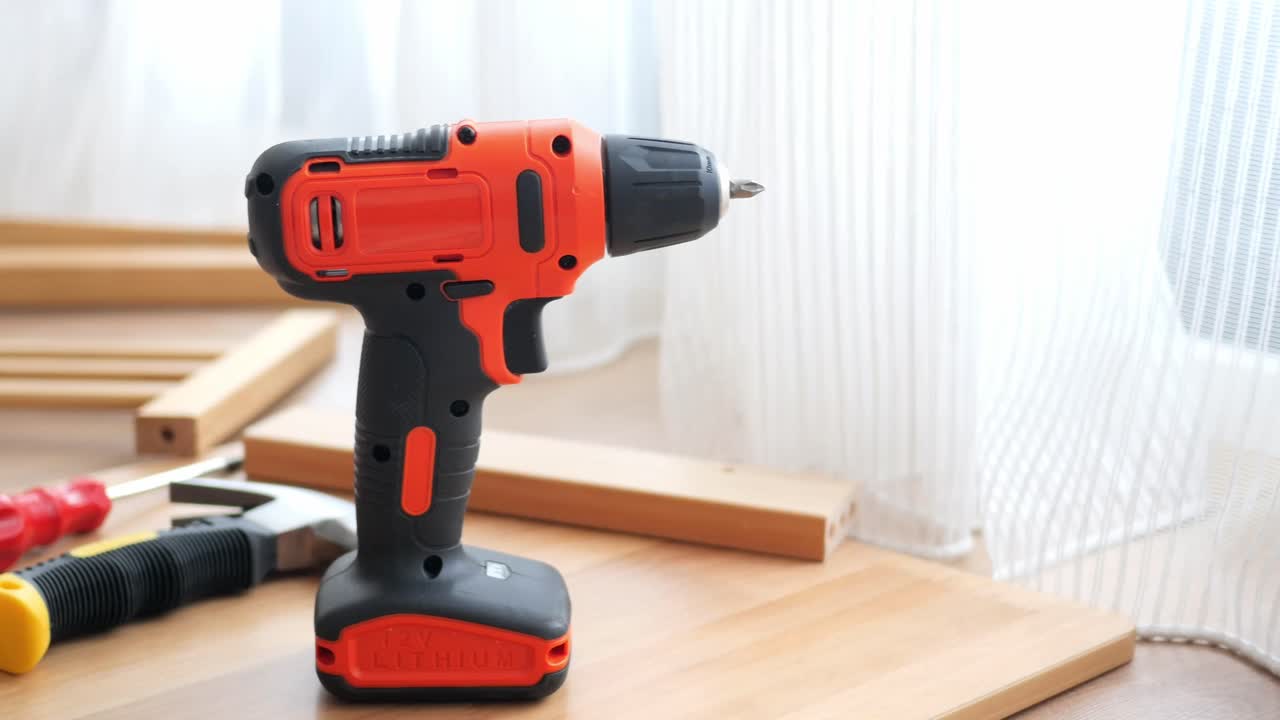 Close-up of a drill and other tools on a wooden surface