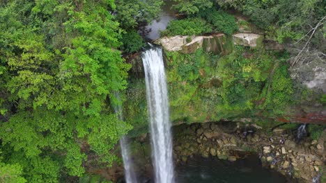 aerial: tropical waterfall cascading over rocky canyon precipice