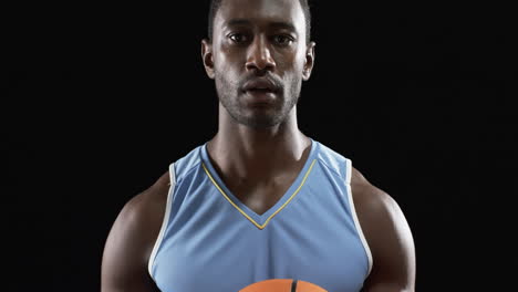 atleta afroamericano enfocado sosteniendo una pelota de baloncesto en fondo negro