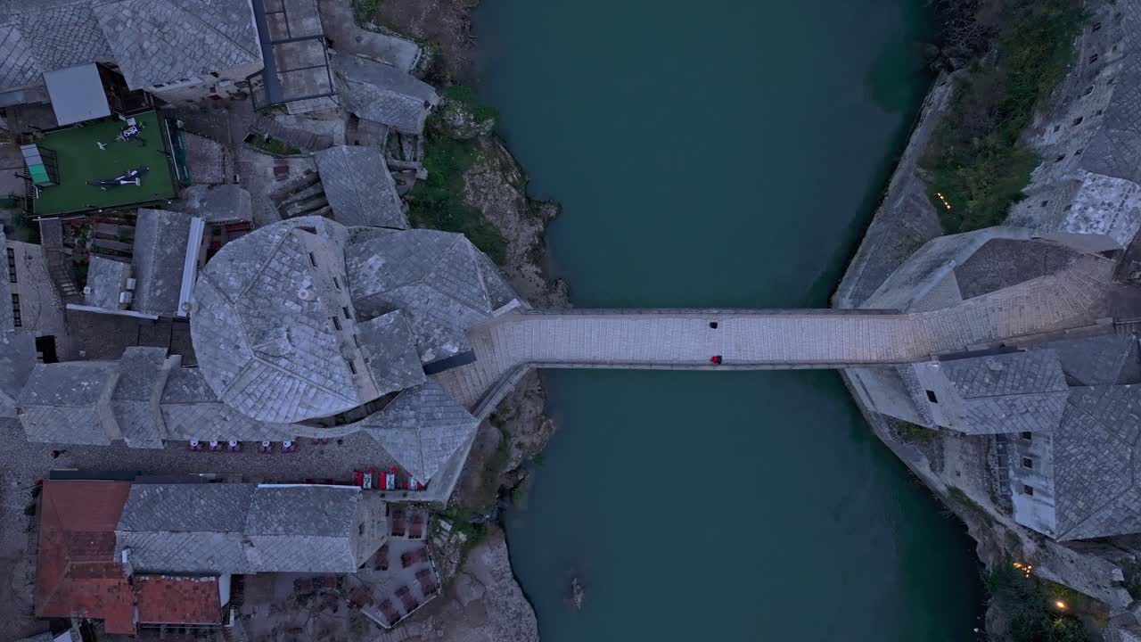 Toma aérea de Stari Most bañado en tonos rosados y naranjas del crepúsculo
